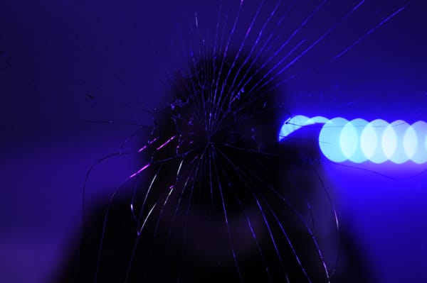white woman with a camera reflected in a broken mirror